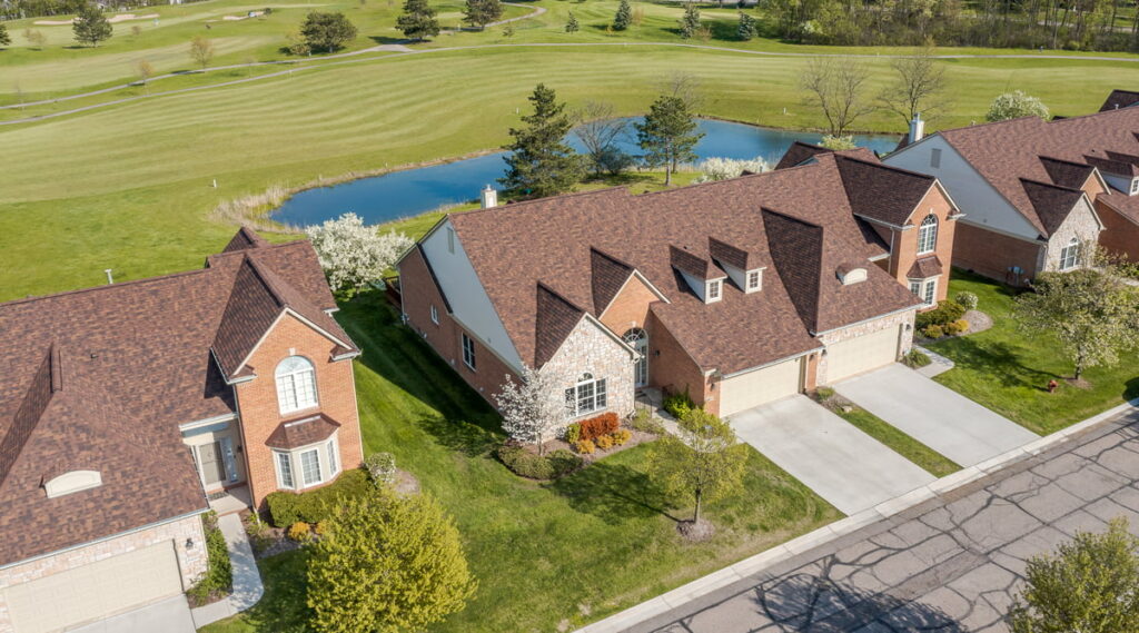 Aerial view of a large ranch home for sale in Farmington MI with plenty of land and a pond in the backyard