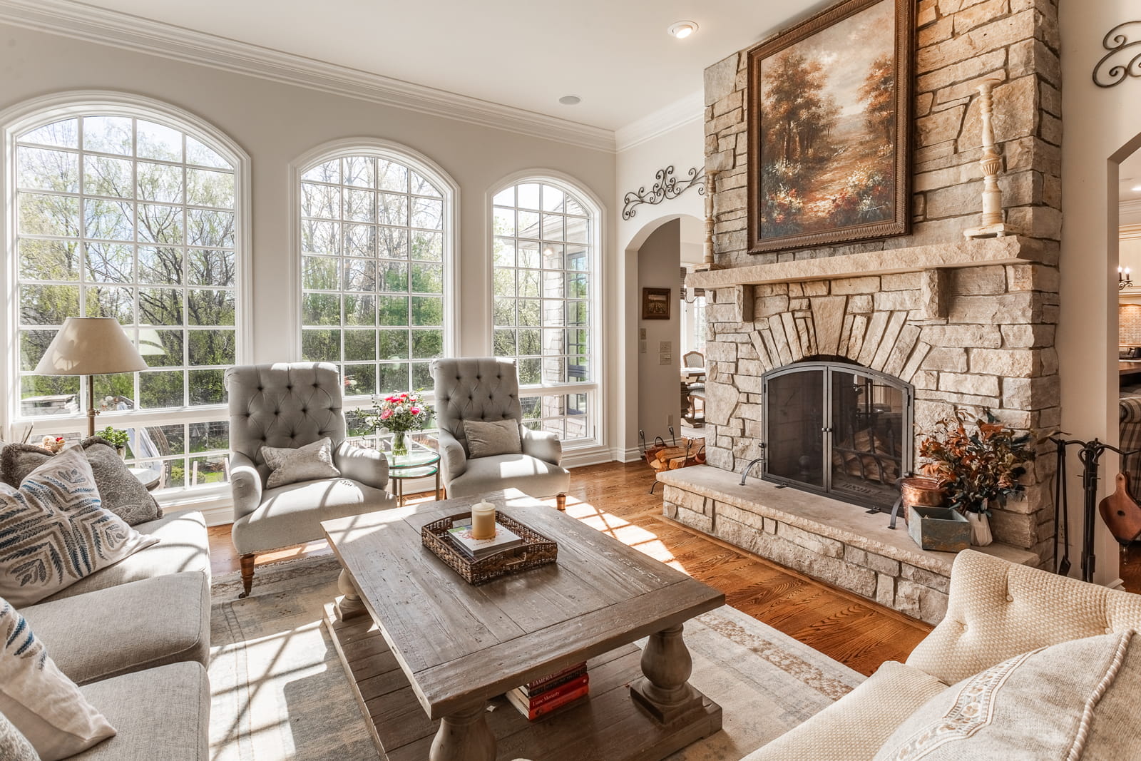 Elegant living room in a Farmington, MI property boasting arched windows, a stone fireplace, and abundant natural light.