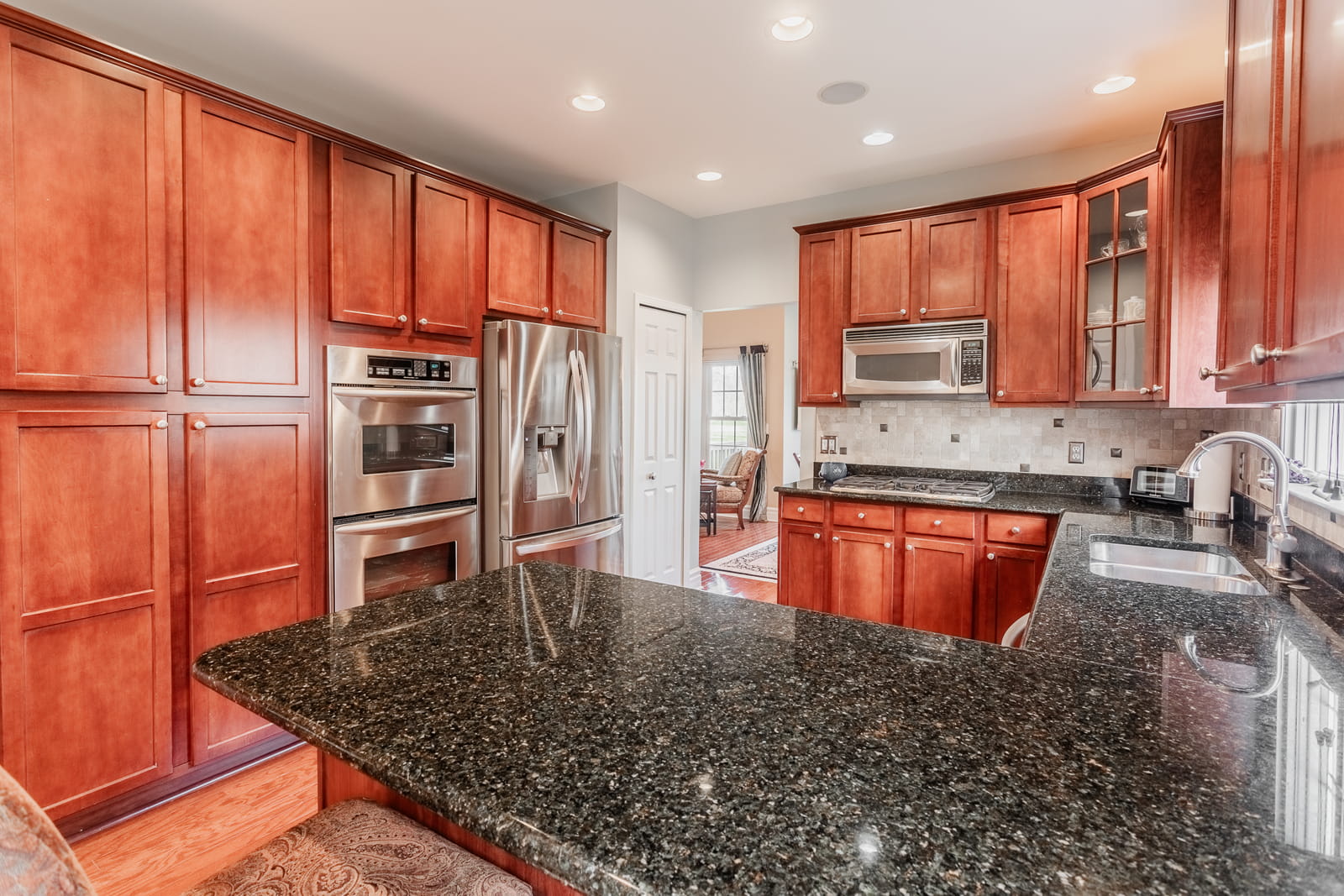 Modern kitchen in Farmington, MI home featuring cherry wood cabinets, granite countertops, and stainless steel appliances