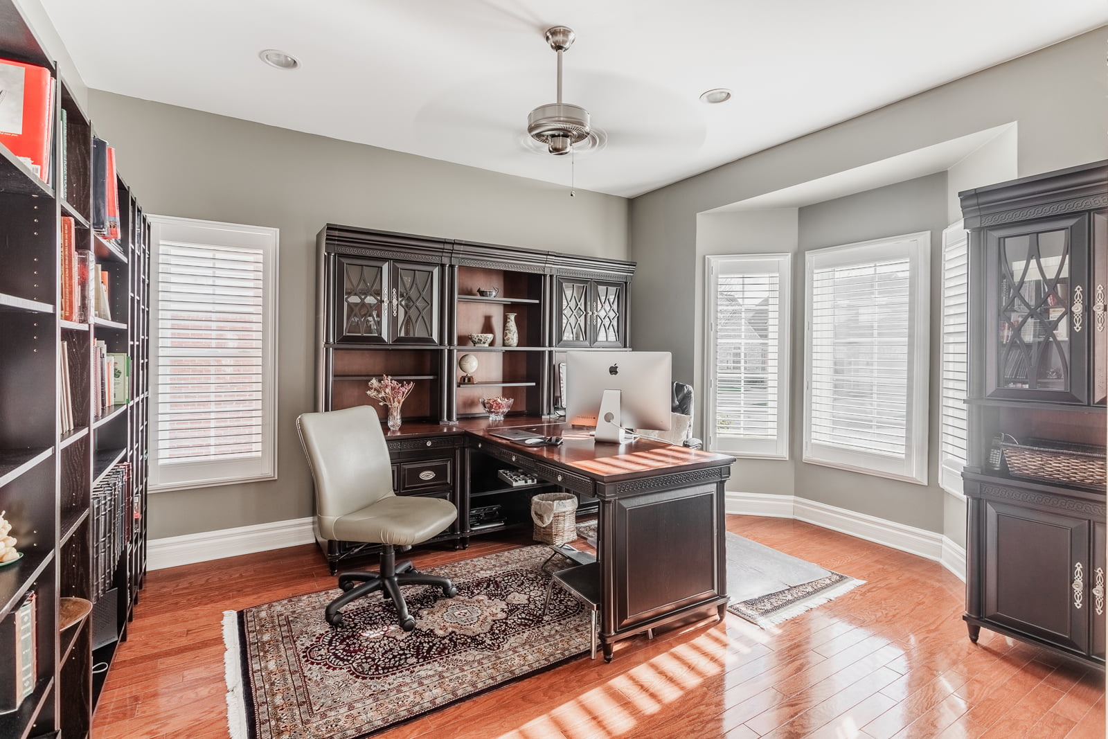 Elegant home office with bay windows, custom wood cabinetry, and built-in shelving in a Farmington, Michigan residence