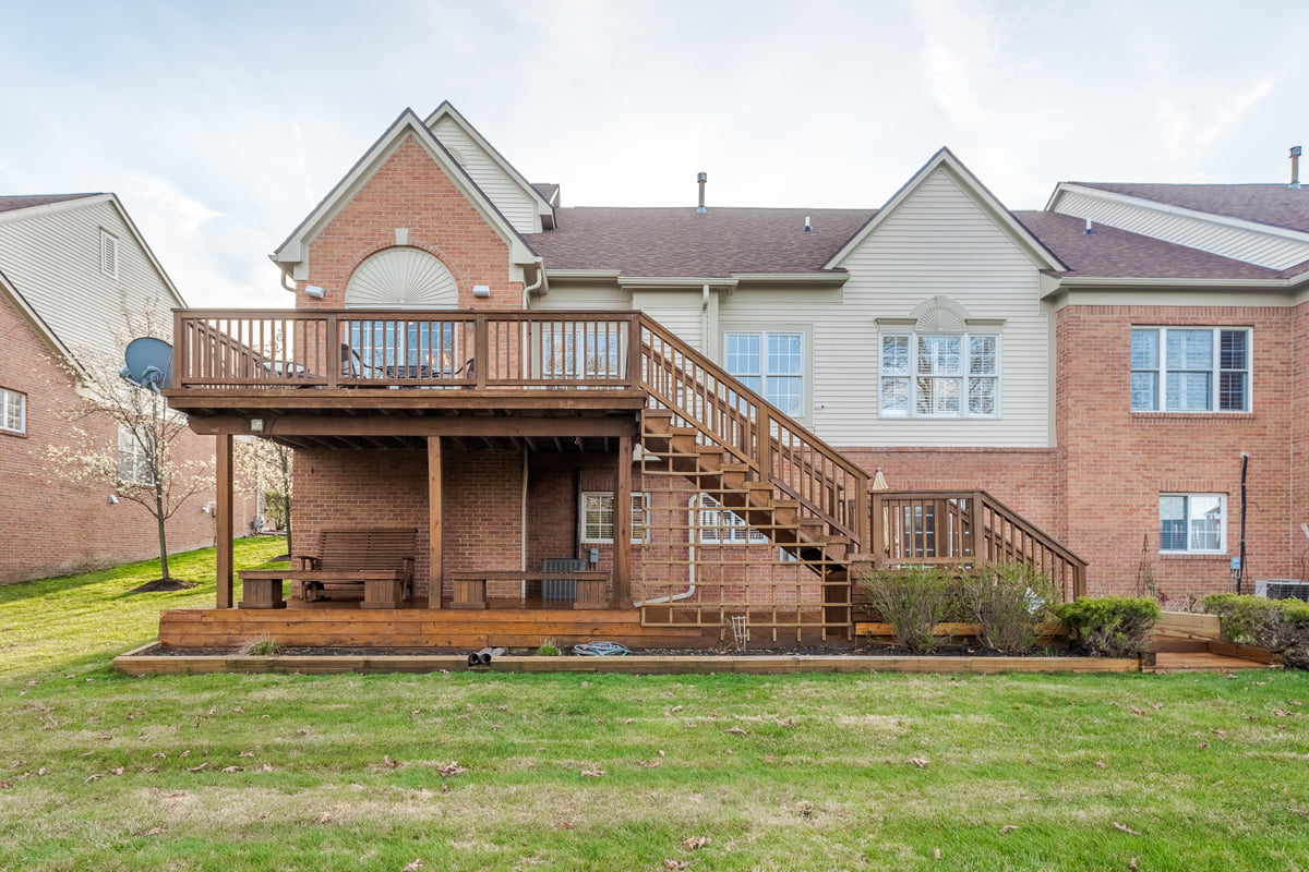 A spacious two-story brick home in Farmington, Michigan with a walk-out lower level and large elevated deck above, perfect for entertaining.