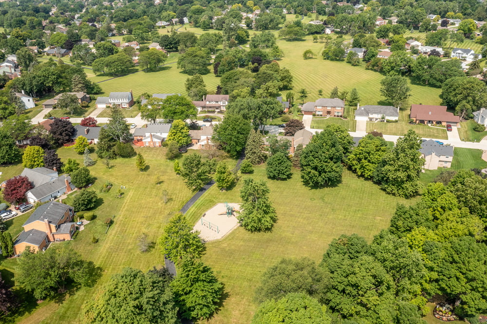 Aerial view of 25410 Liberty in Farmington Hills showing surrounding homes, mature trees, open green space, and a neighborhood playground.