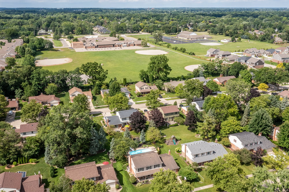 Aerial view of 46174 Forestwood in Plymouth showing surrounding homes, mature trees, and sports fields.