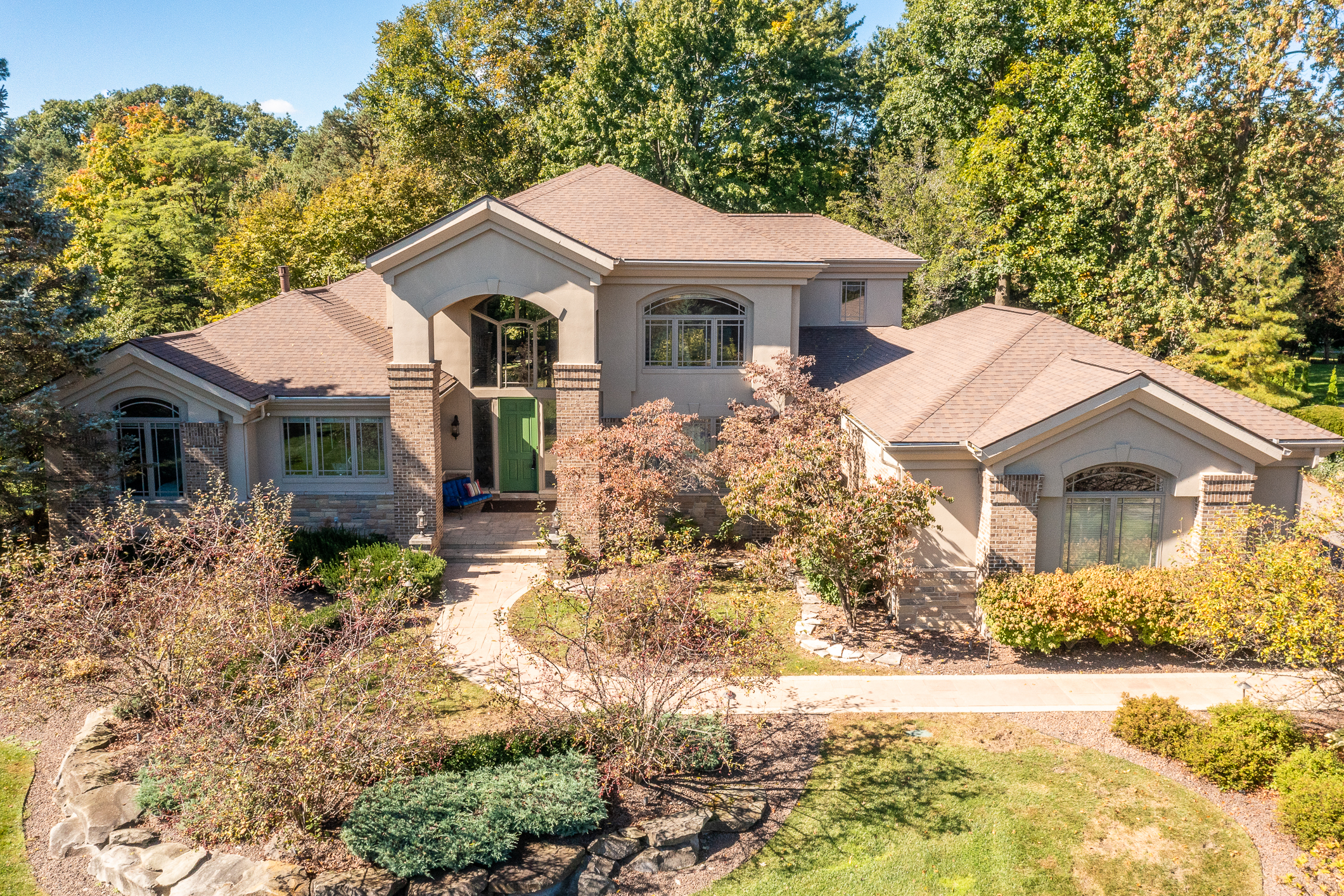 Luxury brick home in Plymouth, Michigan with landscaped front yard, and wooded backyard.