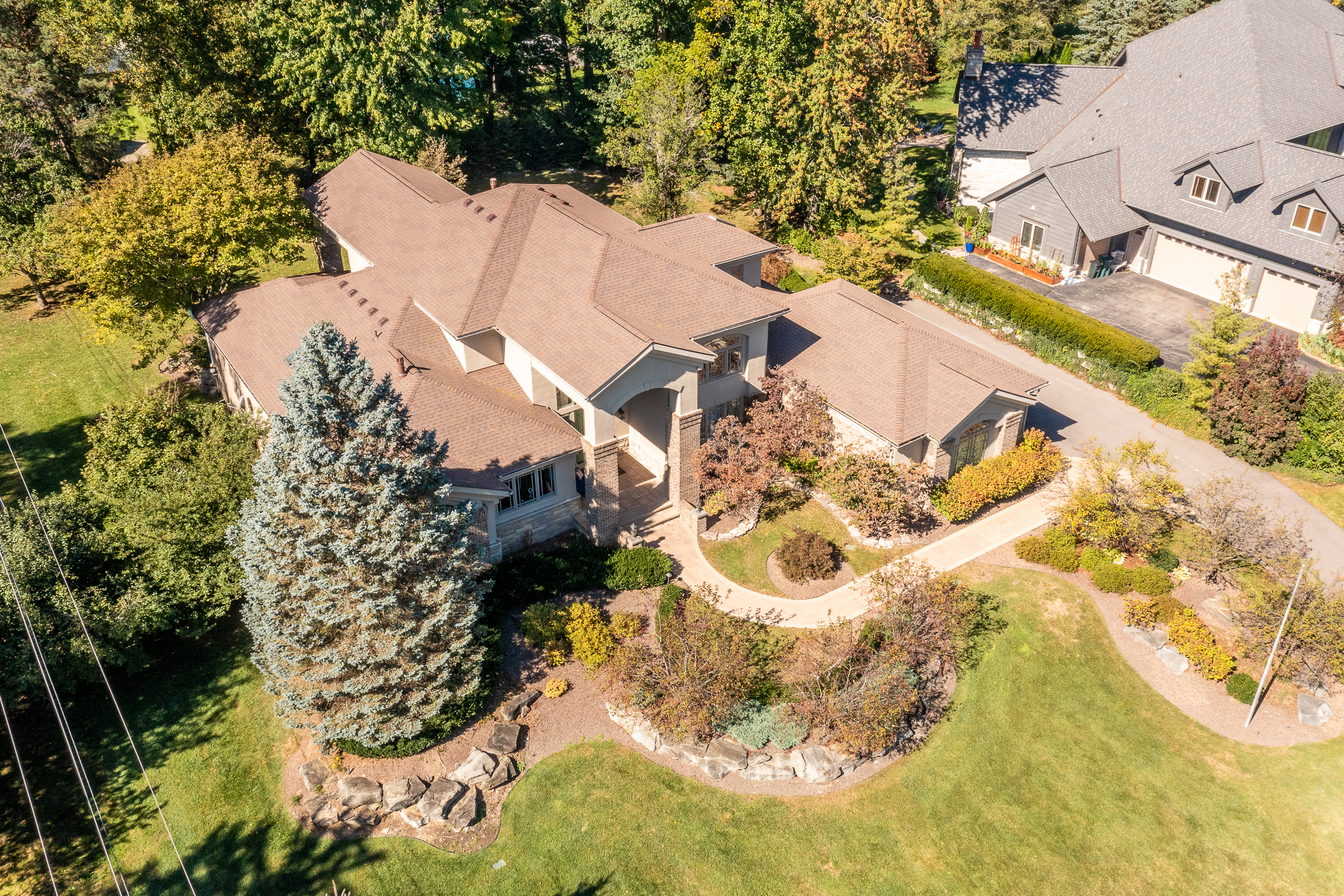 Aerial view of a large Plymouth, MI home with mature trees, extensive landscaping, and a spacious residential lot