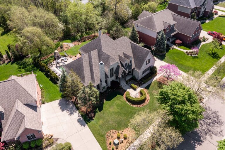 Large home with mature trees and a landscaped front yard in Farmington, Michigan.