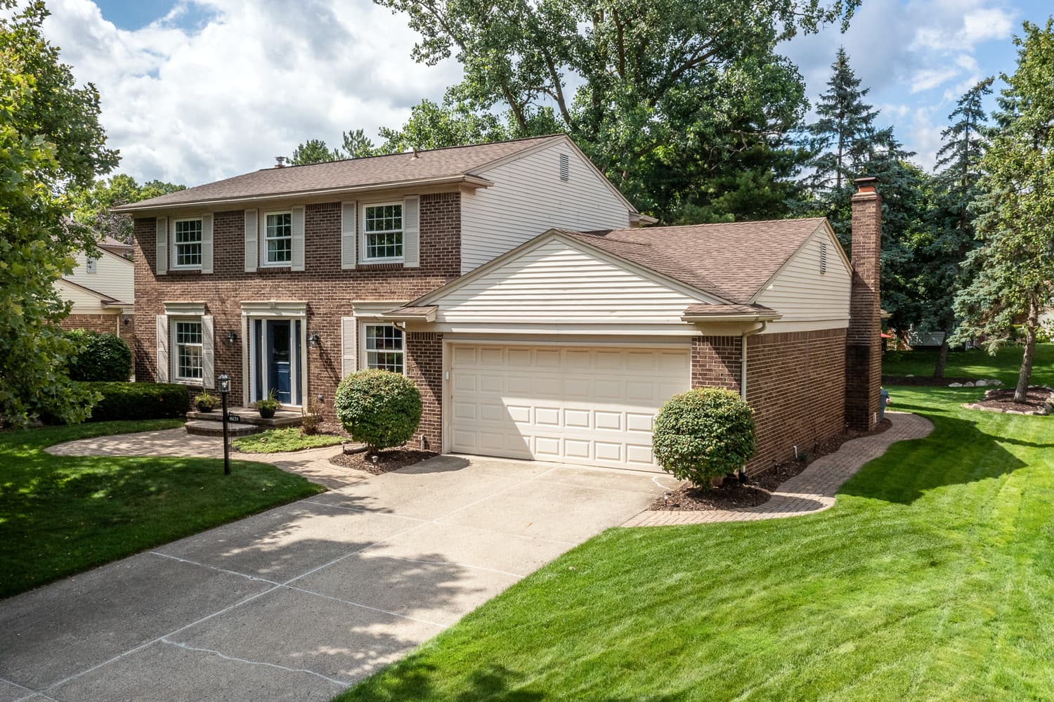 Traditional home with a landscaped front yard and mature trees in a Plymouth, Michigan neighborhood.